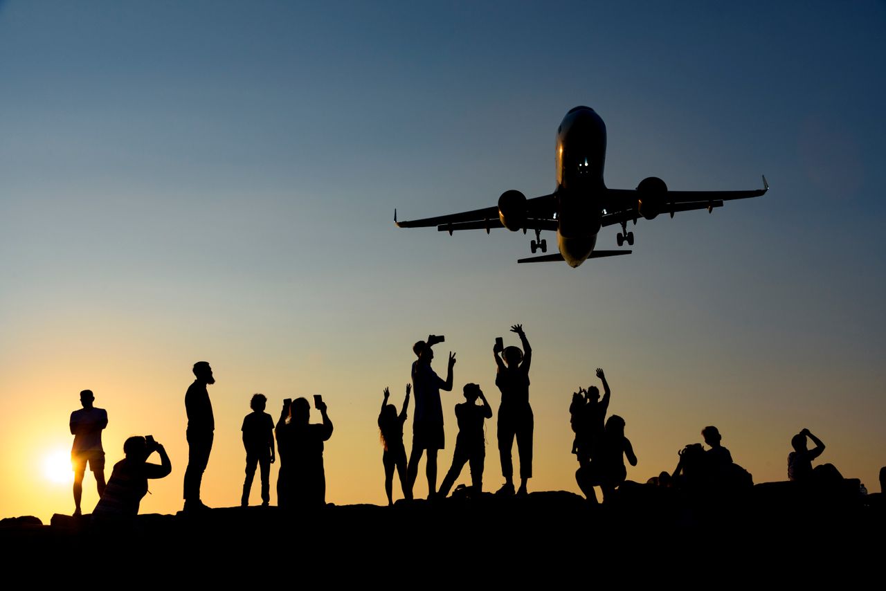 digital-01 A dynamic silhouette of people photographing an airplane during a vibrant sunset.