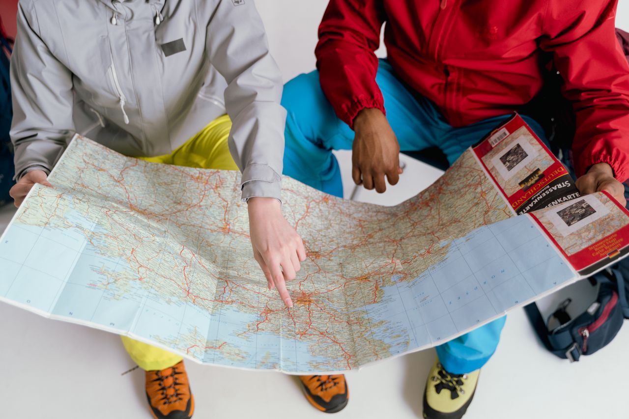 brand-03 Two travelers examining a detailed map for a winter hiking adventure.