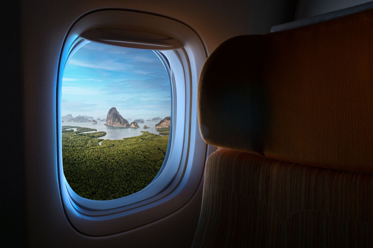 Breathtaking airplane window view of Phang-nga's lush landscape and limestone cliffs.